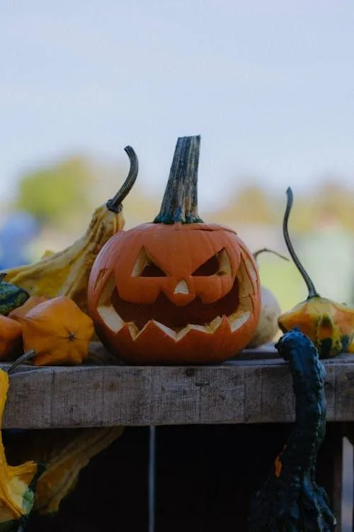 Pumpkin with Carved Face on Rustic Wooden Table Wallpaper