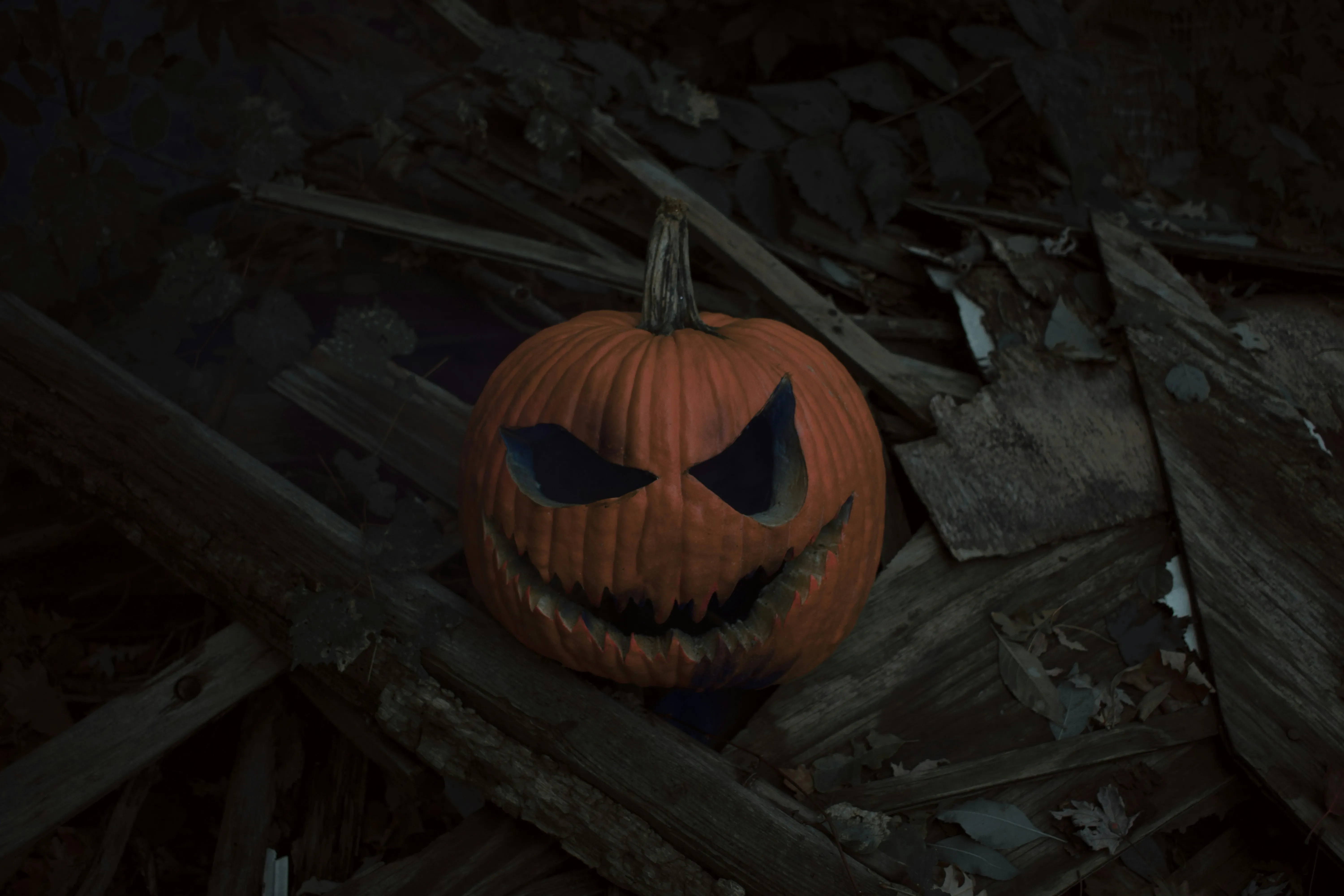 Scary Pumpkin on Dark Wood Floor with Evil Grin Wallpaper