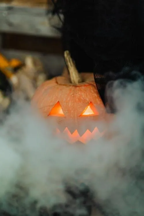 Smoky Halloween Scene with Carved Glowing Pumpkin Image