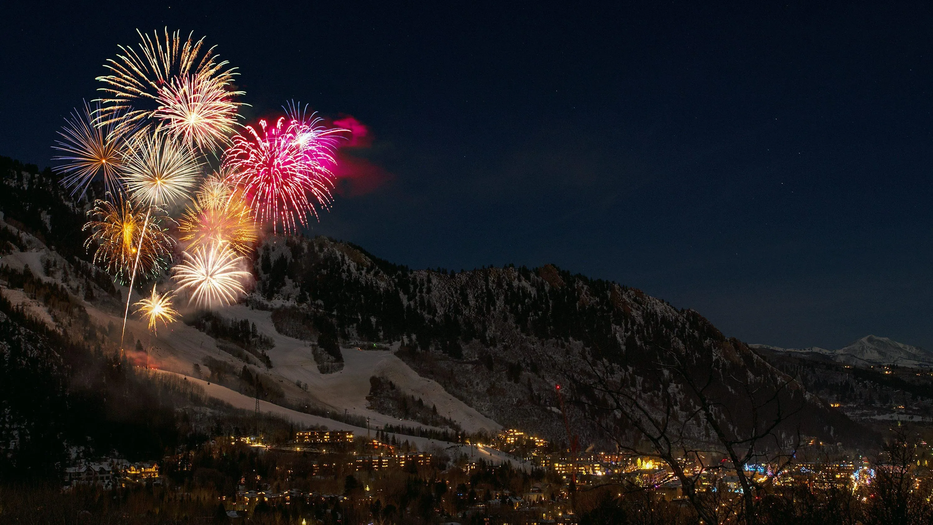 Snowy mountain backdrop with vibrant fireworks lighting up