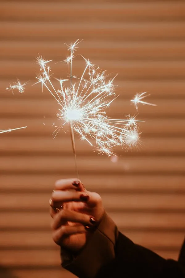 Sparkler in Hand Creating Bright Patterns Against Dark Background