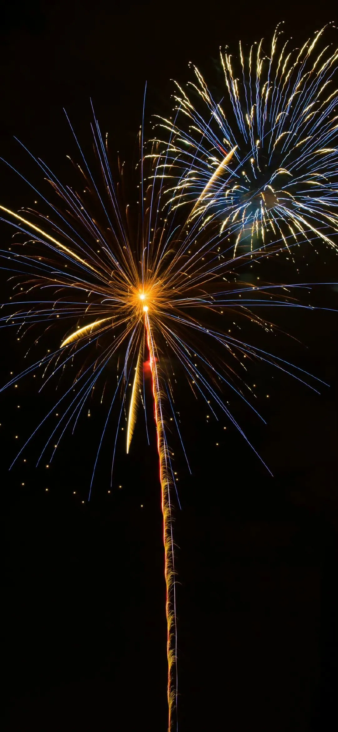 Sparkling fireworks bursting in dark sky with golden light