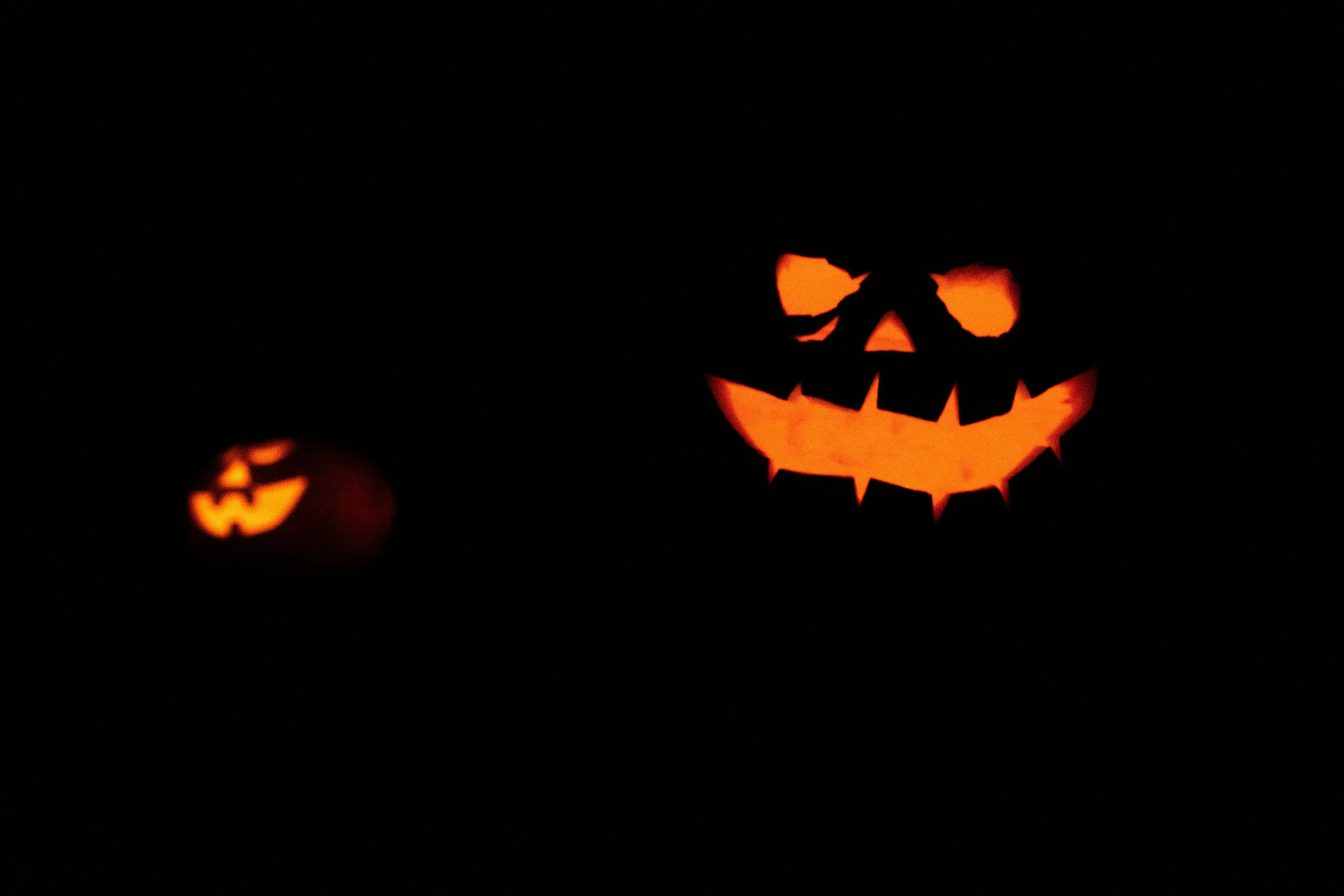 Spooky Glowing Jack O Lantern Faces in Darkness Wallpaper