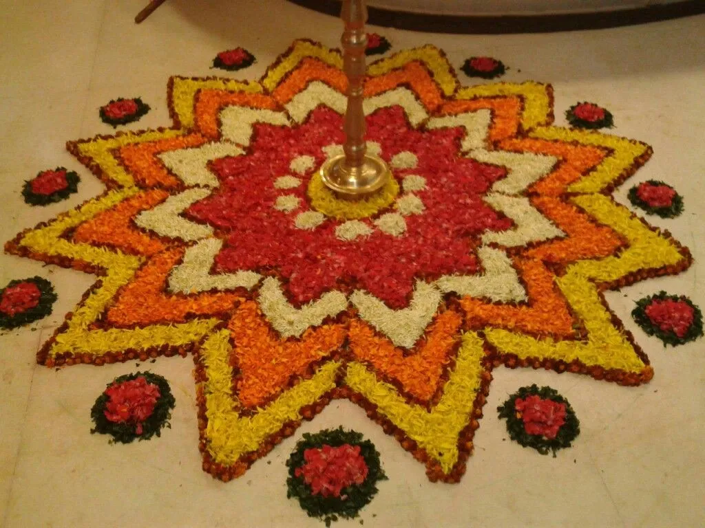 Sun pattern layered Onam Athapookolam with a brass lamp