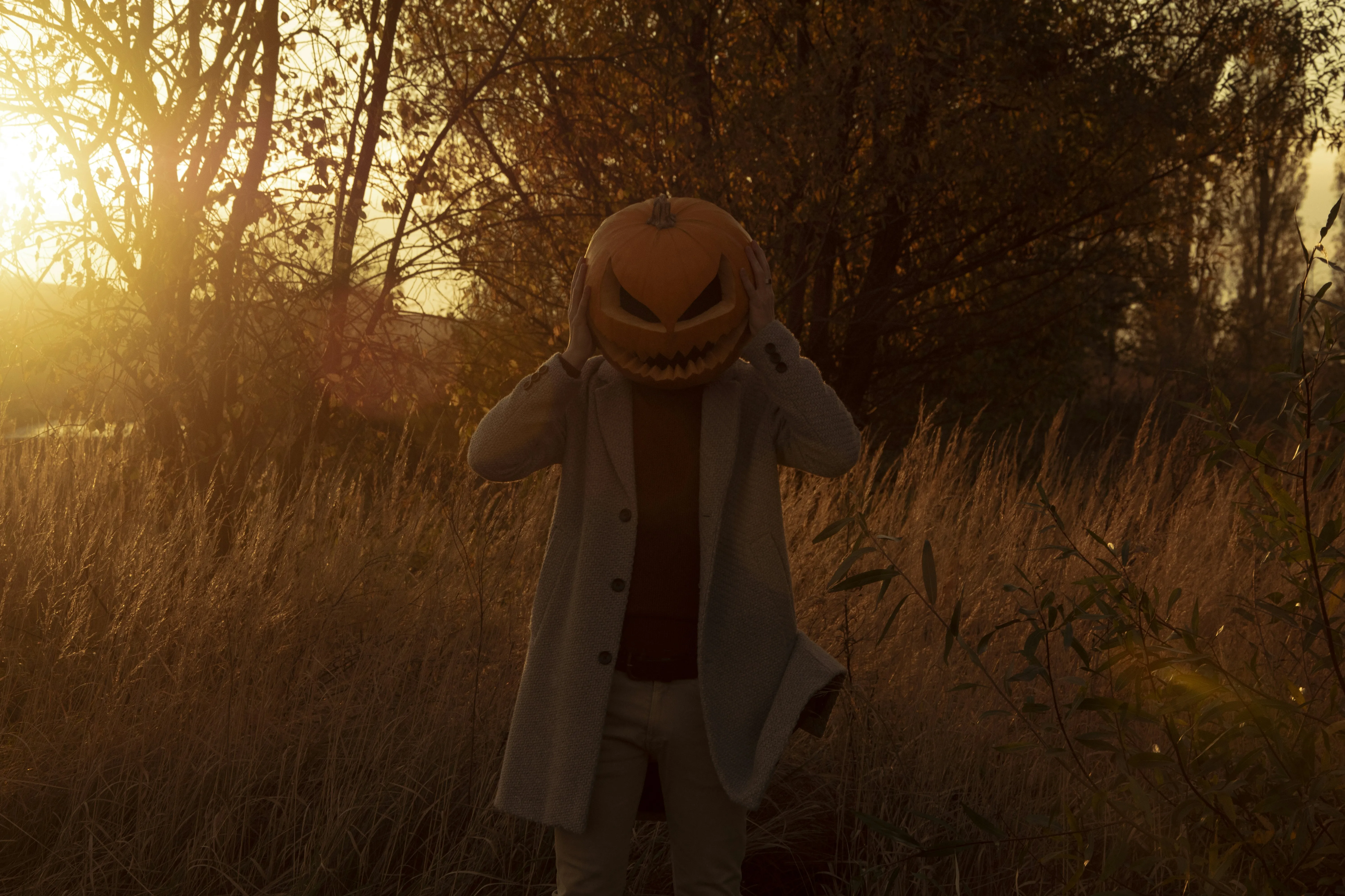Sunset Halloween Scene with Person in Pumpkin Mask Wallpaper
