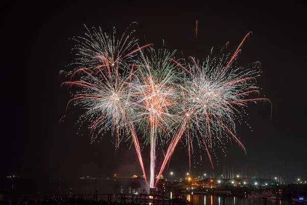 Symmetrical Fireworks Bursting over Water in Bright Colors