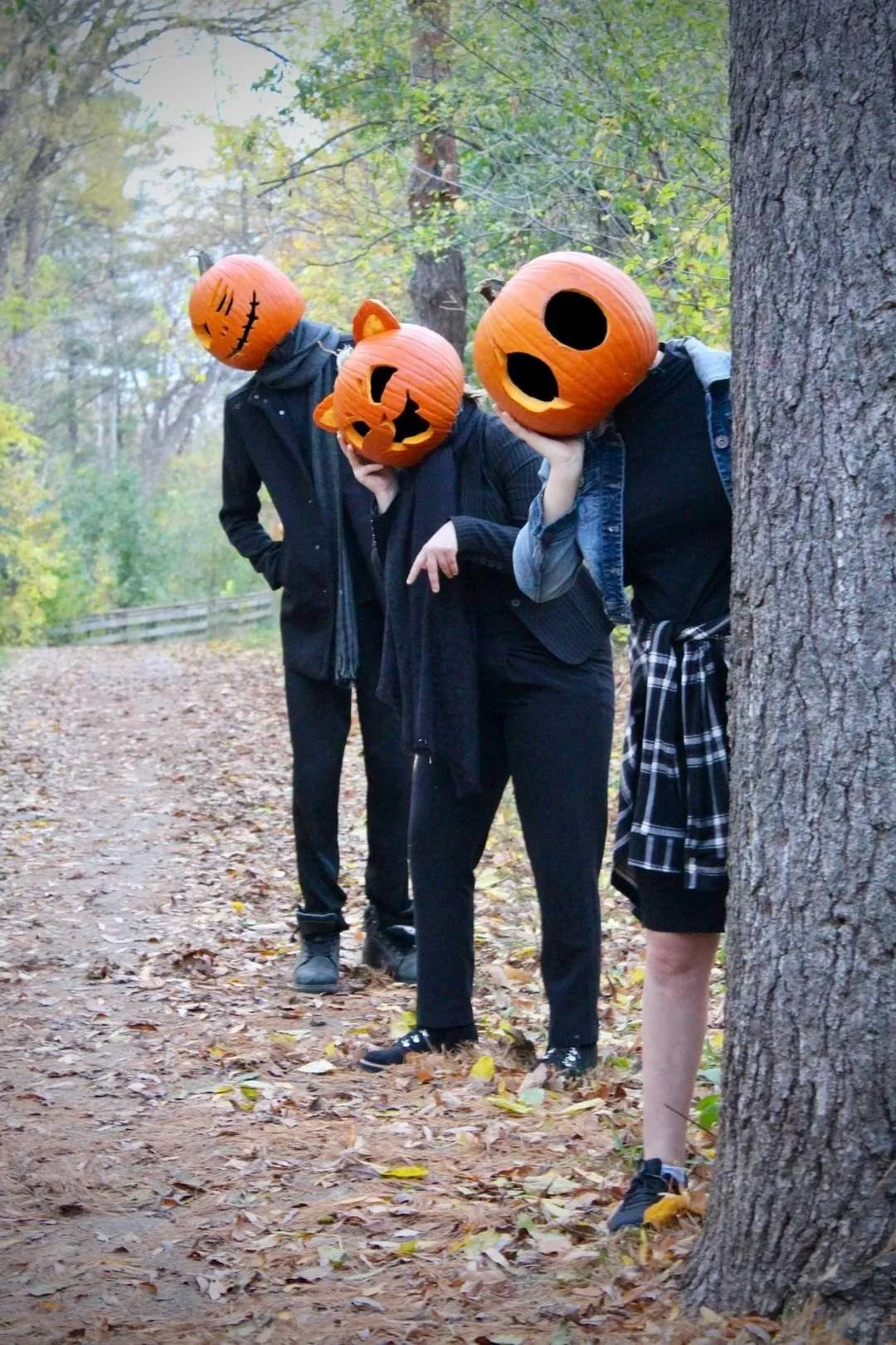 Three People Wearing Pumpkin Masks in Forest Wallpaper