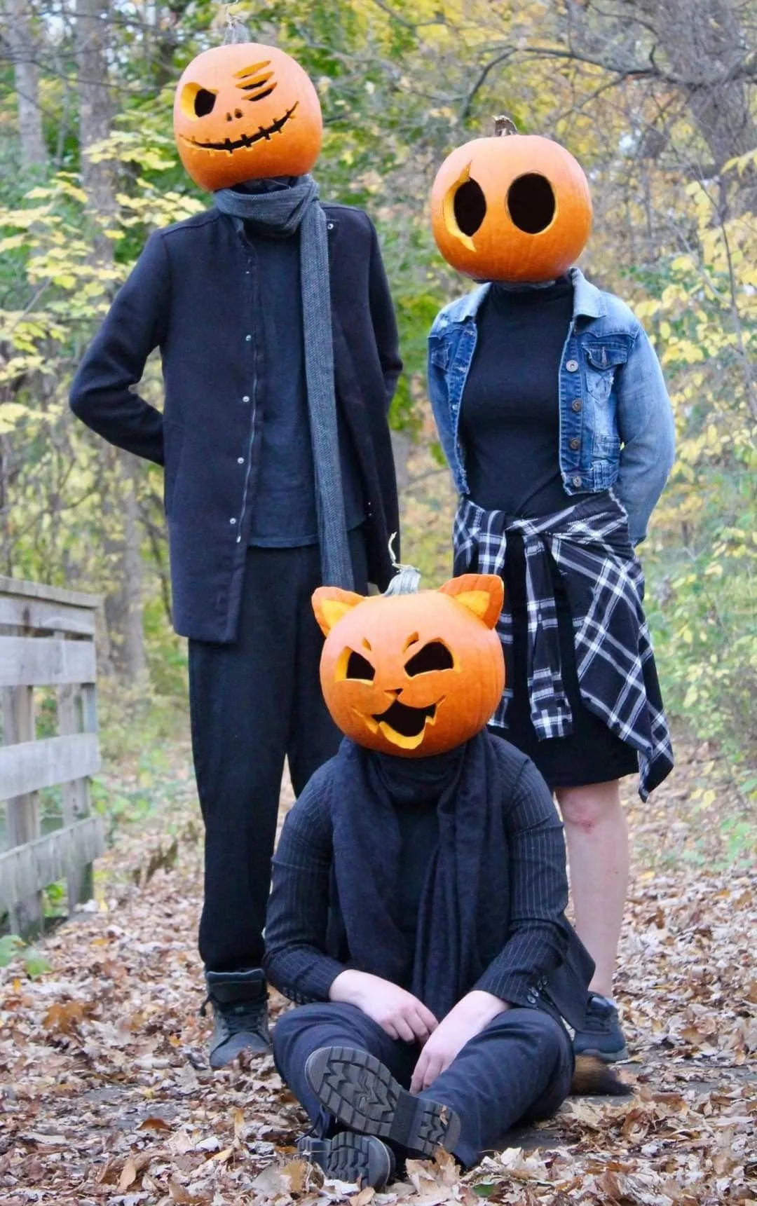 Three People Wearing Pumpkin Masks Posing Outdoors