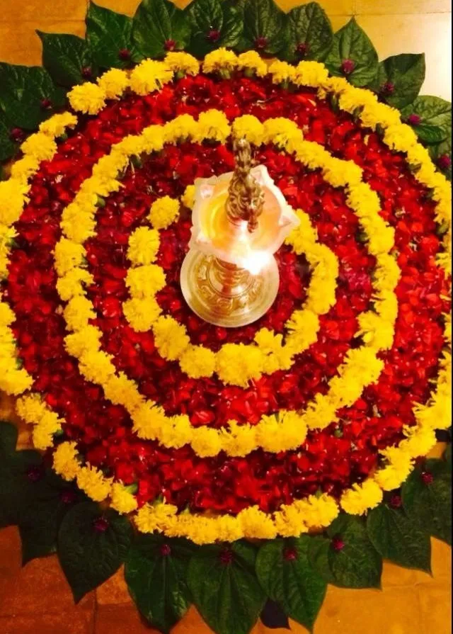 Top view of a red and yellow circular petal pookolam design