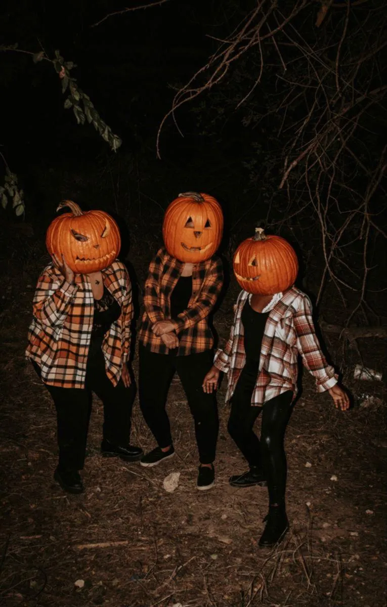 Trio Wearing Pumpkin Head Costumes Walking at Night
