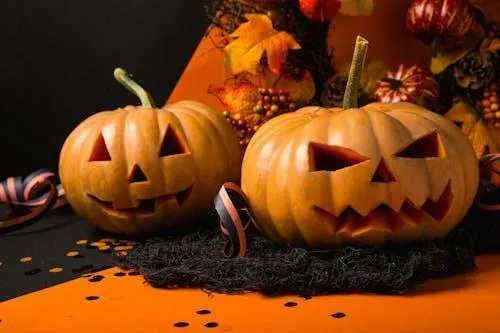 Two Carved Pumpkins with Autumn Leaves on Black Cloth