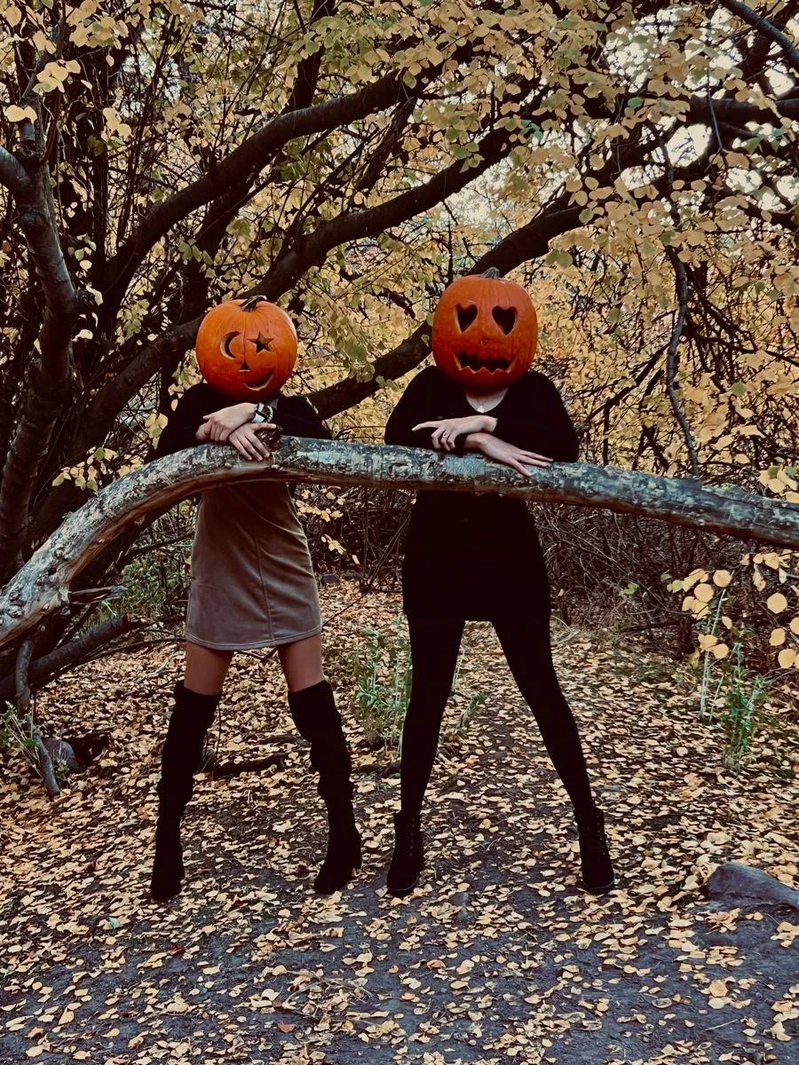 Two Friends in Pumpkin Heads Jumping Together in Woods