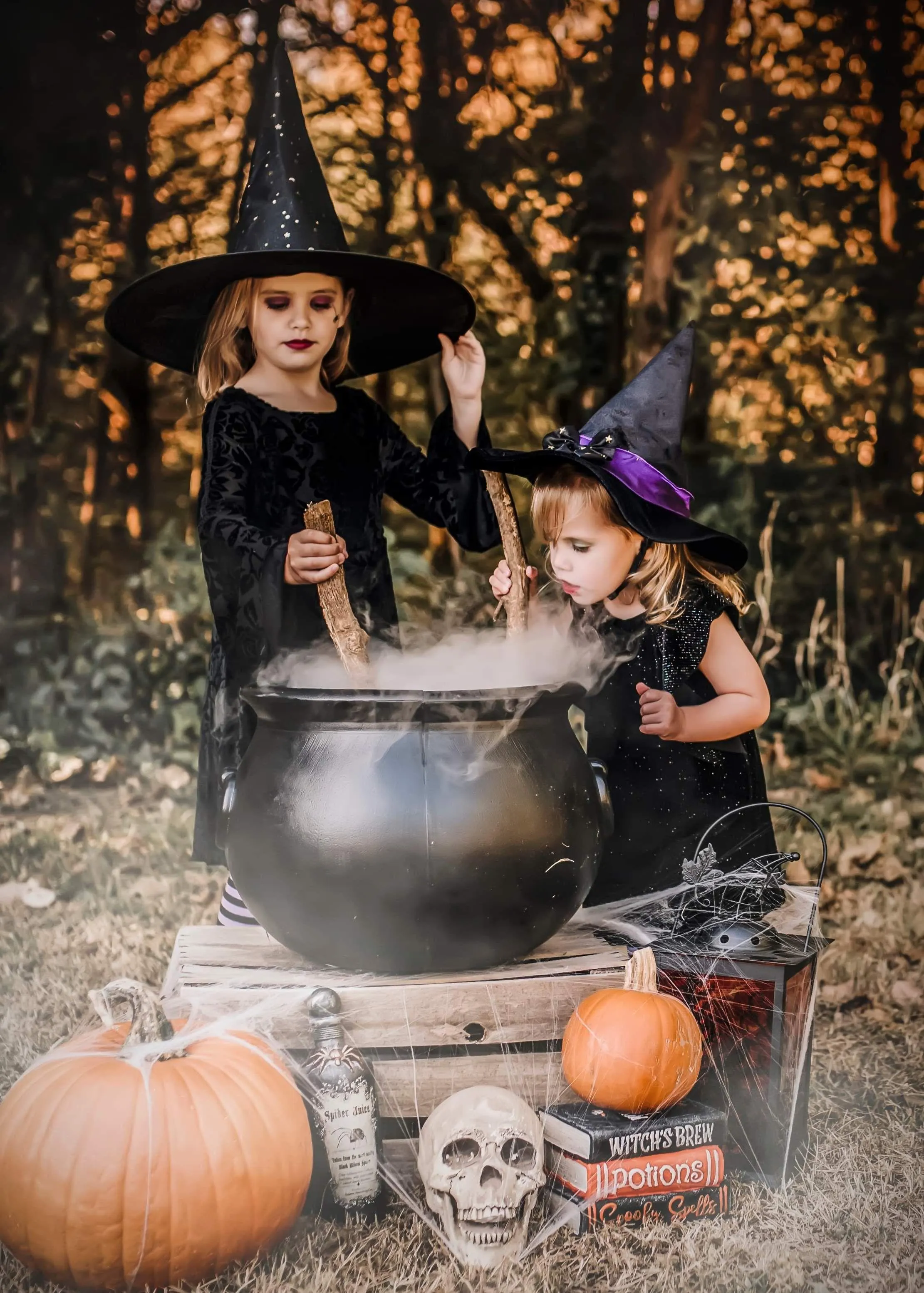 Two Girls in Witch Costumes Near Halloween Cauldron
