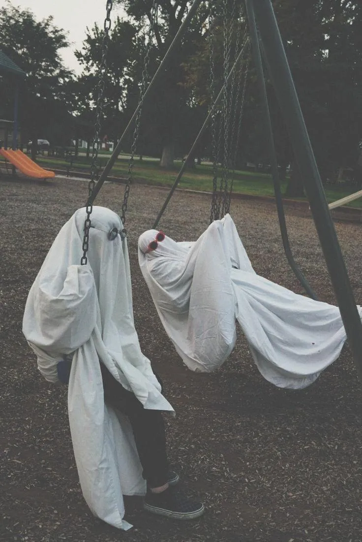 Two Kids Dressed as Ghosts Swinging Outside Wallpaper