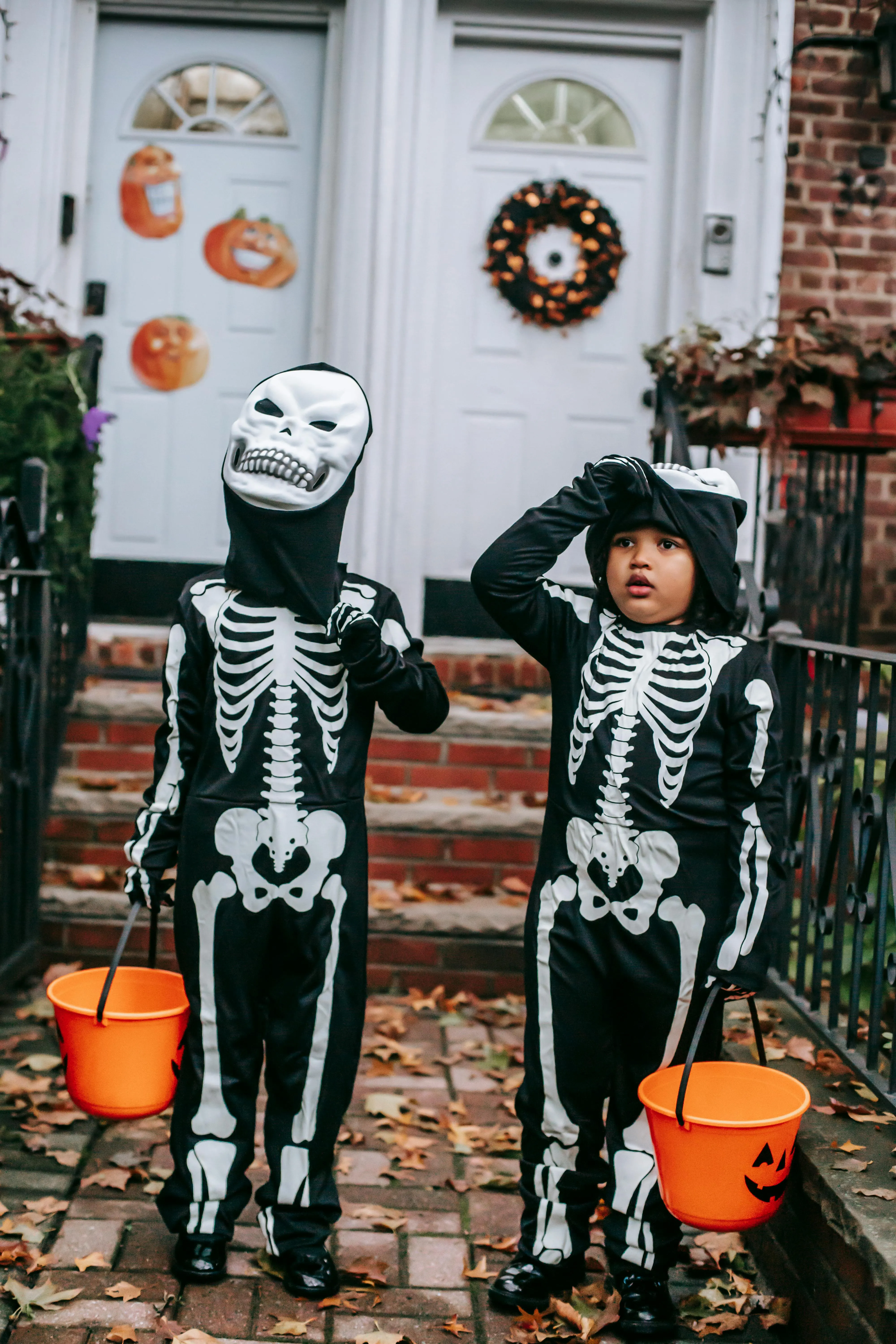 Two Kids Wearing Skeleton Costumes Holding Pumpkin Buckets