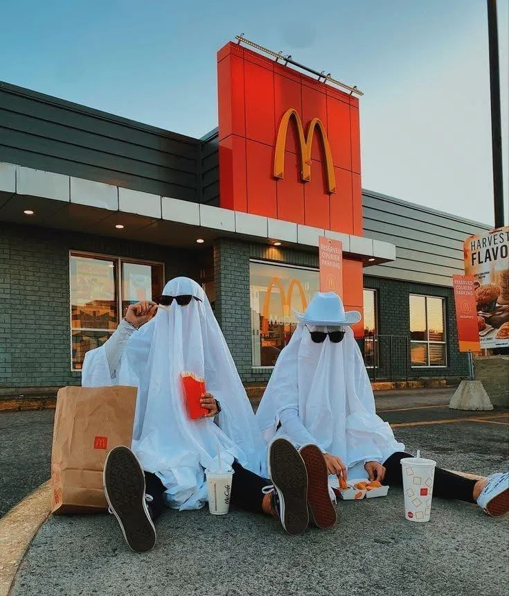 Two People Dressed as Ghosts Eating Outside McDonalds