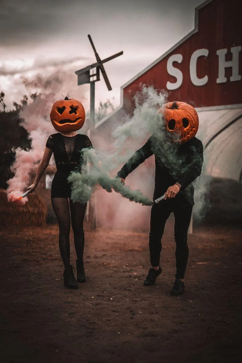Two People Holding Hands with Pumpkin Head Masks on Road