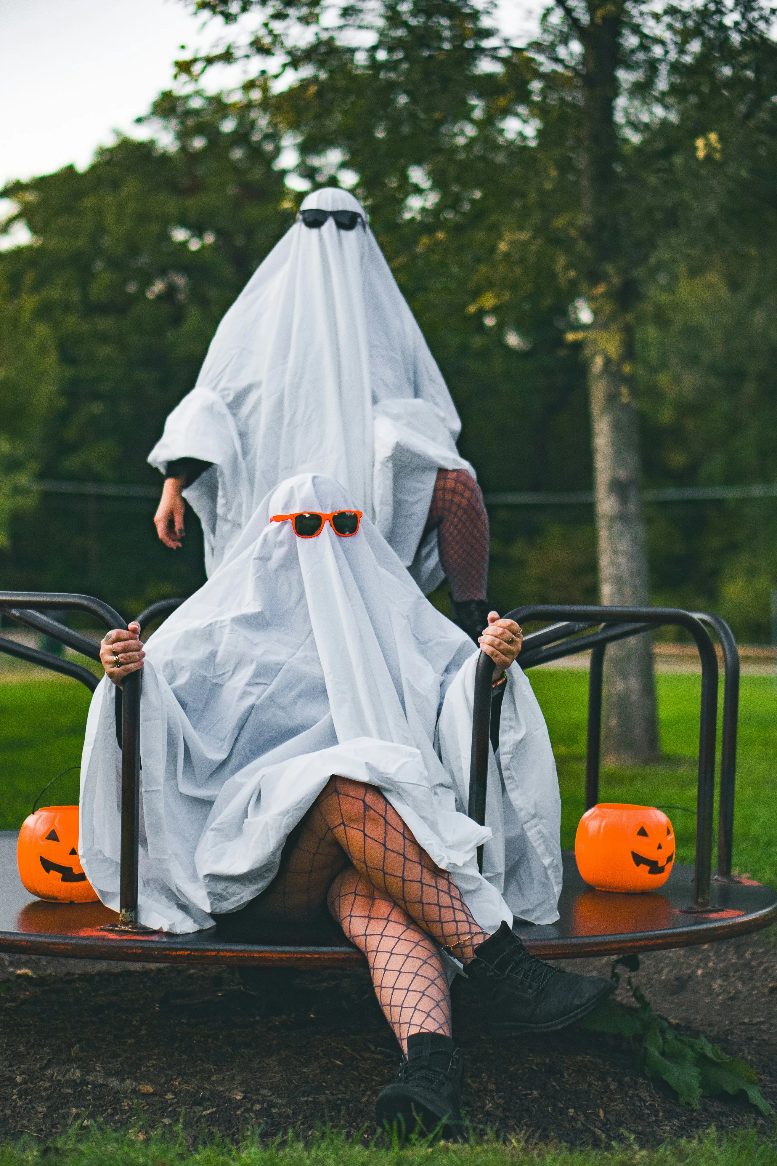 Two People in Ghost Costumes Sitting on Playground image
