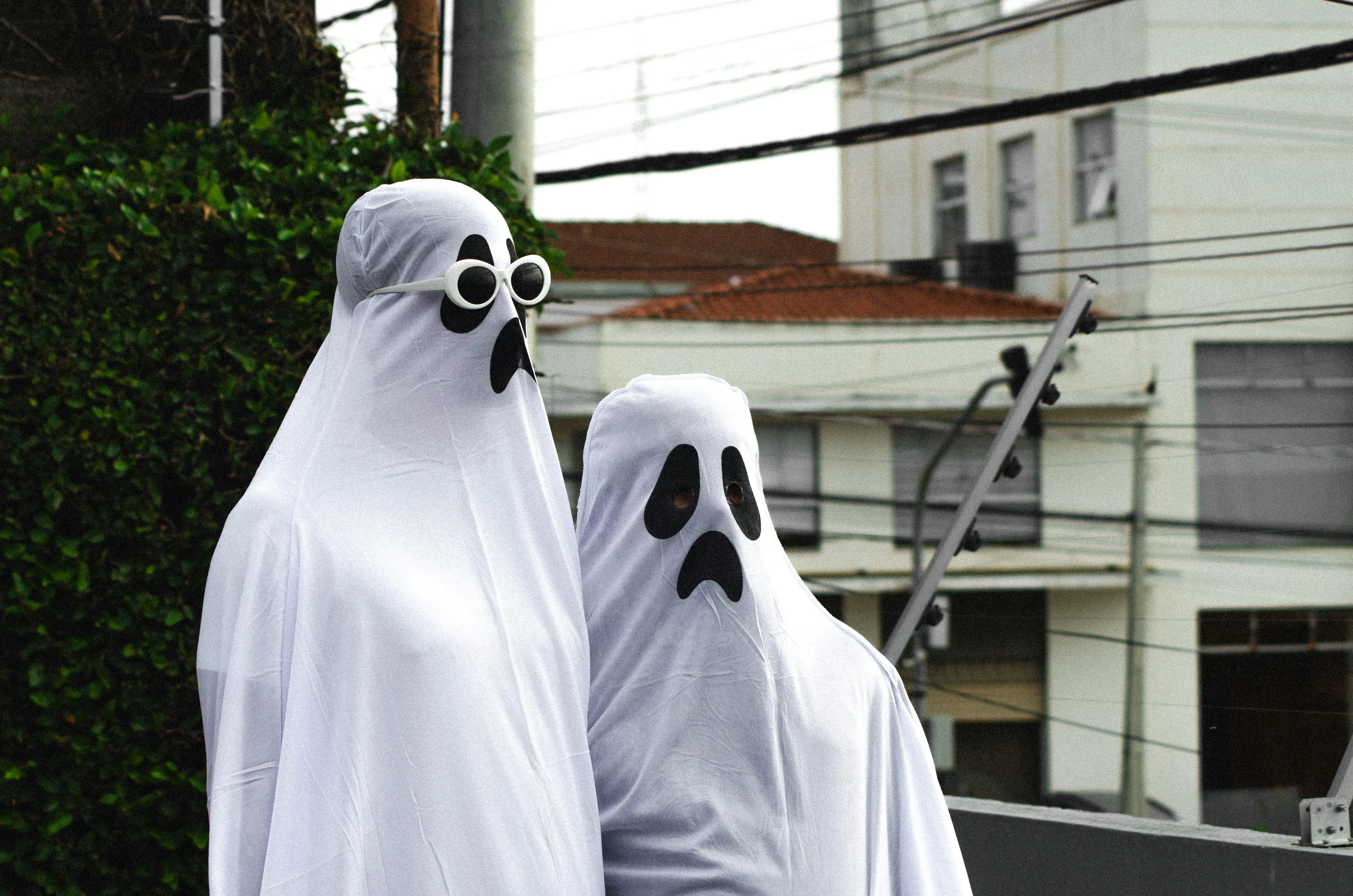 Two People in Ghost Costumes Walking Outside Wallpaper