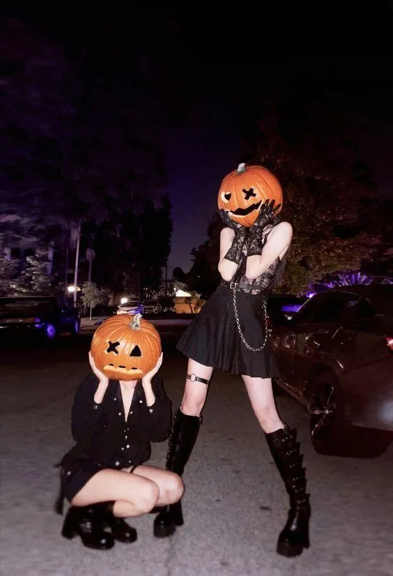 Two people in Halloween outfits with pumpkin heads HD