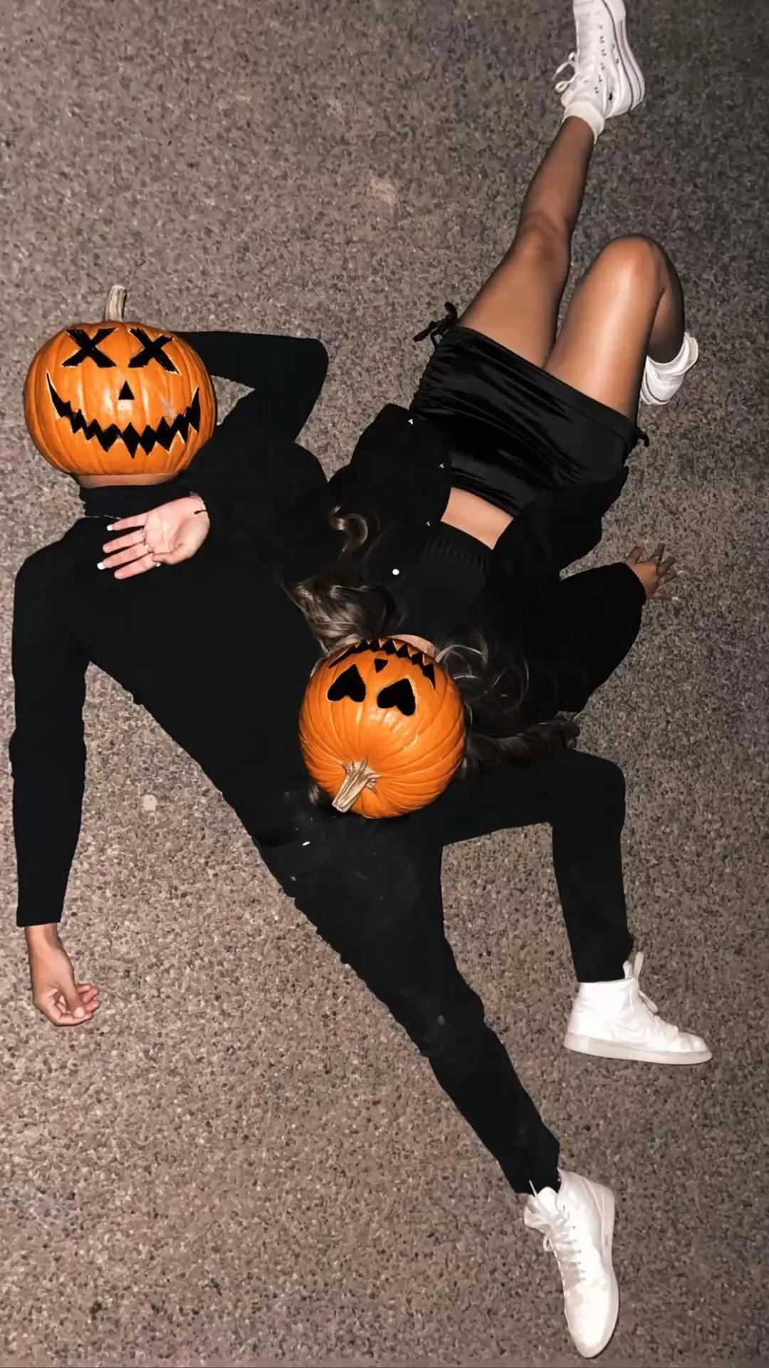 Two People in Pumpkin Masks Lying on Ground Wallpaper