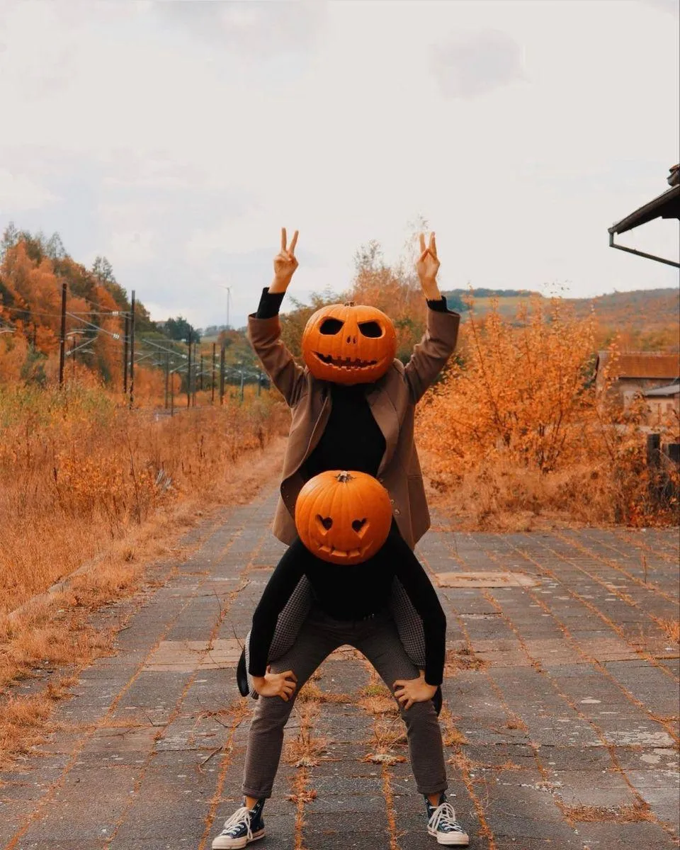 Two People Wearing Carved Pumpkin Heads on a Rustic Path