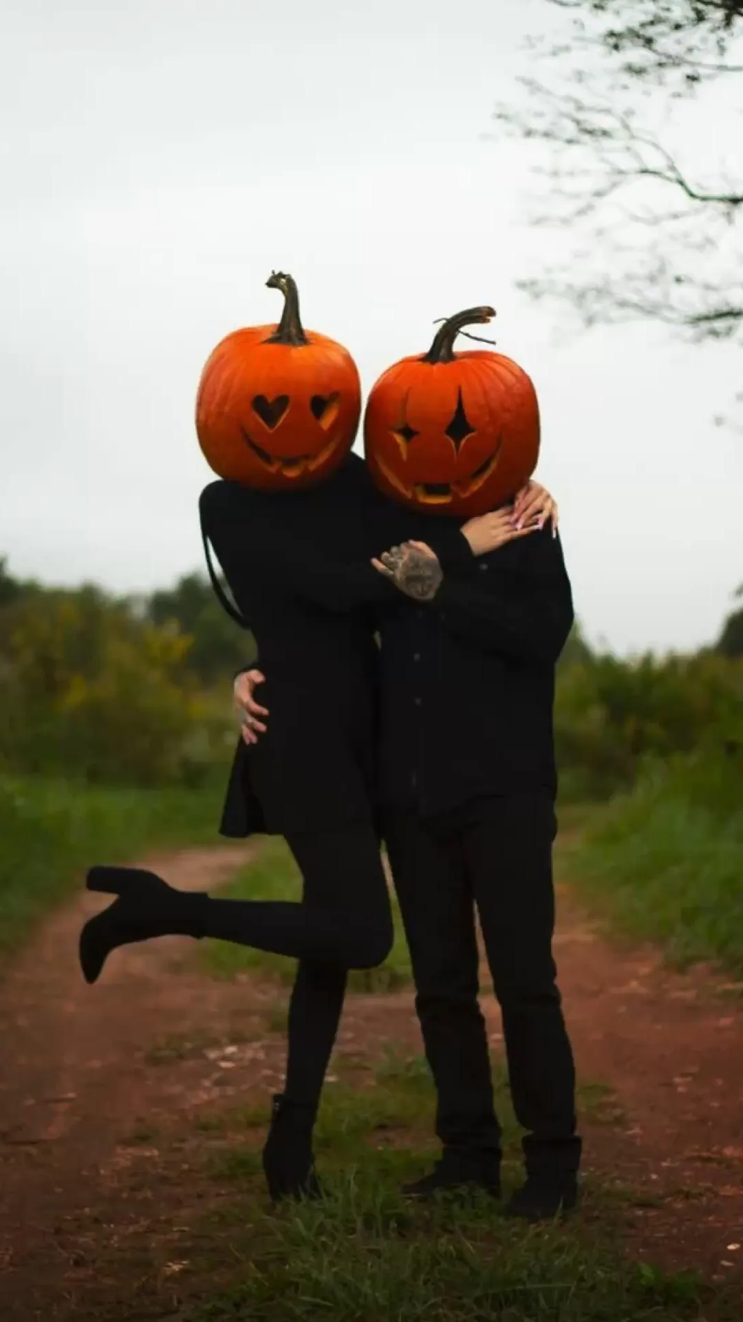 Two People Wearing Pumpkin Head Masks in Outdoor Setting