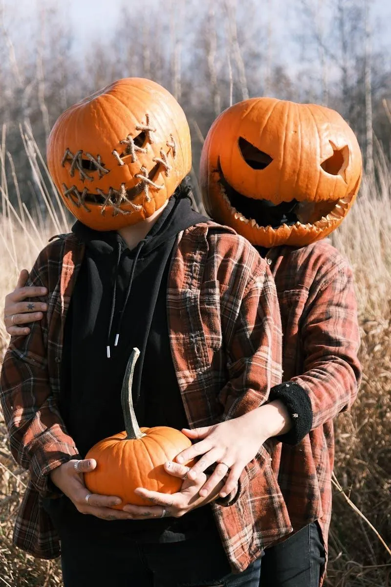 Two People Wearing Pumpkin Heads Holding Pumpkin Outdoors