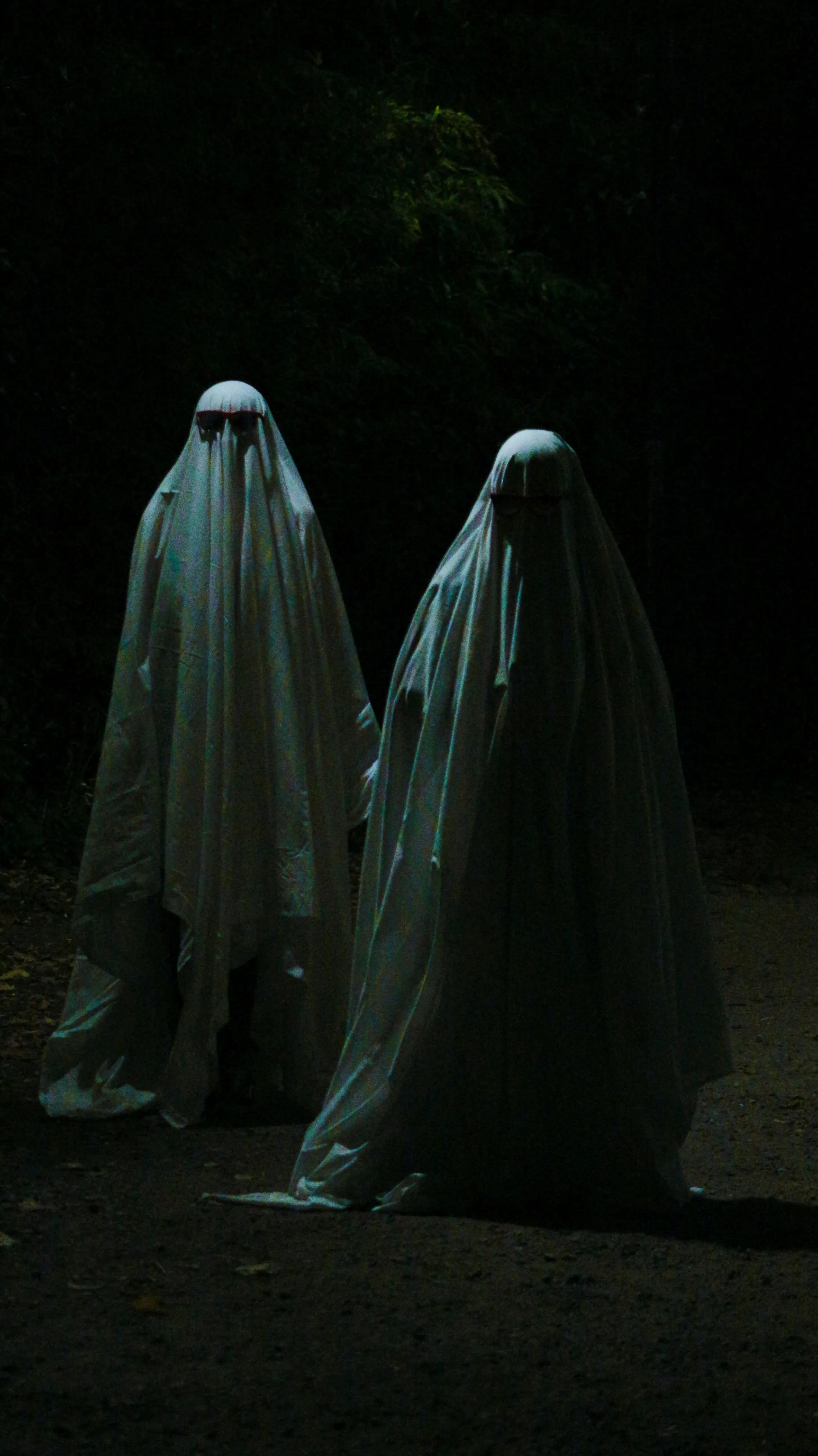 Two Tall Ghost Figures in Dark Halloween Atmosphere