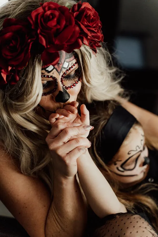 Two women with floral crowns and face paint in close view