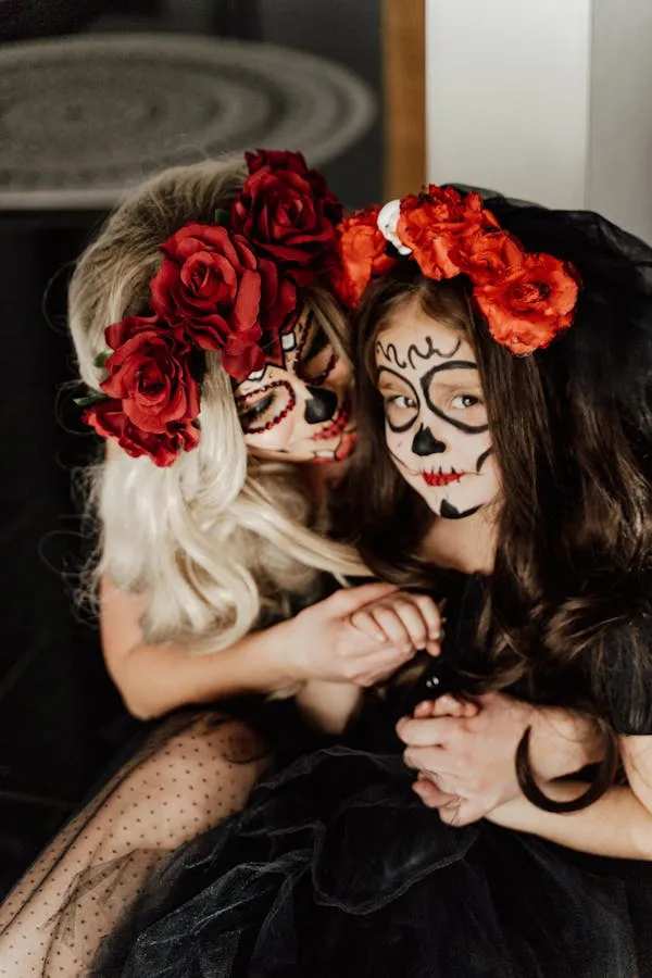 Two women with skull makeup and floral crowns embracing
