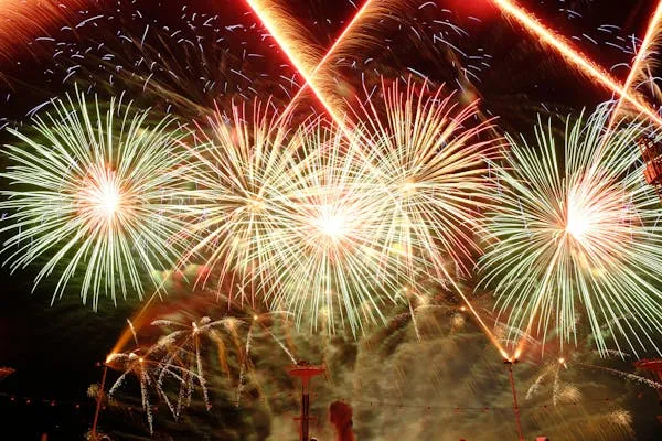 Vibrant fireworks bursting over the city at night Wallpaper