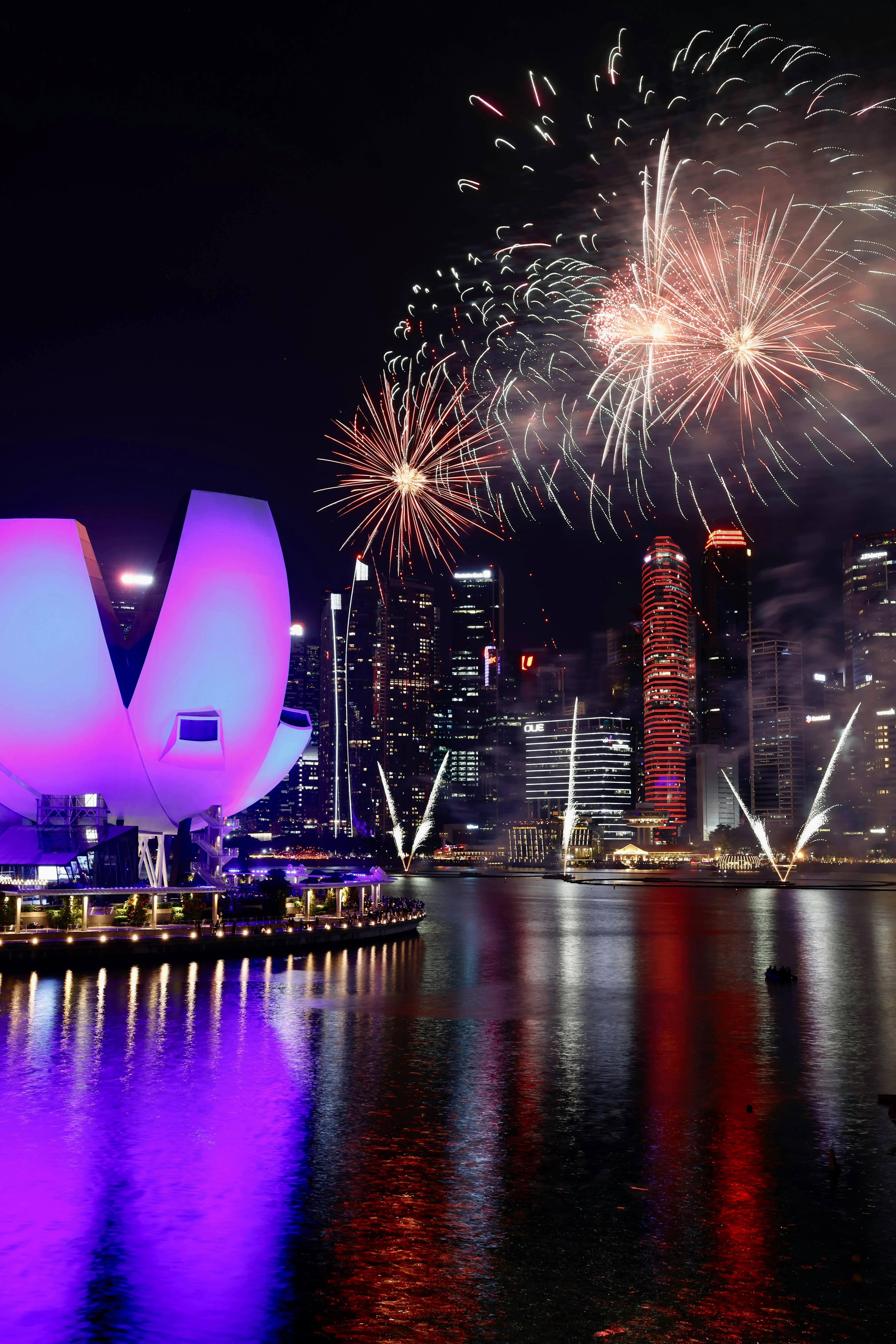 Vibrant fireworks over a city skyline at night with reflections