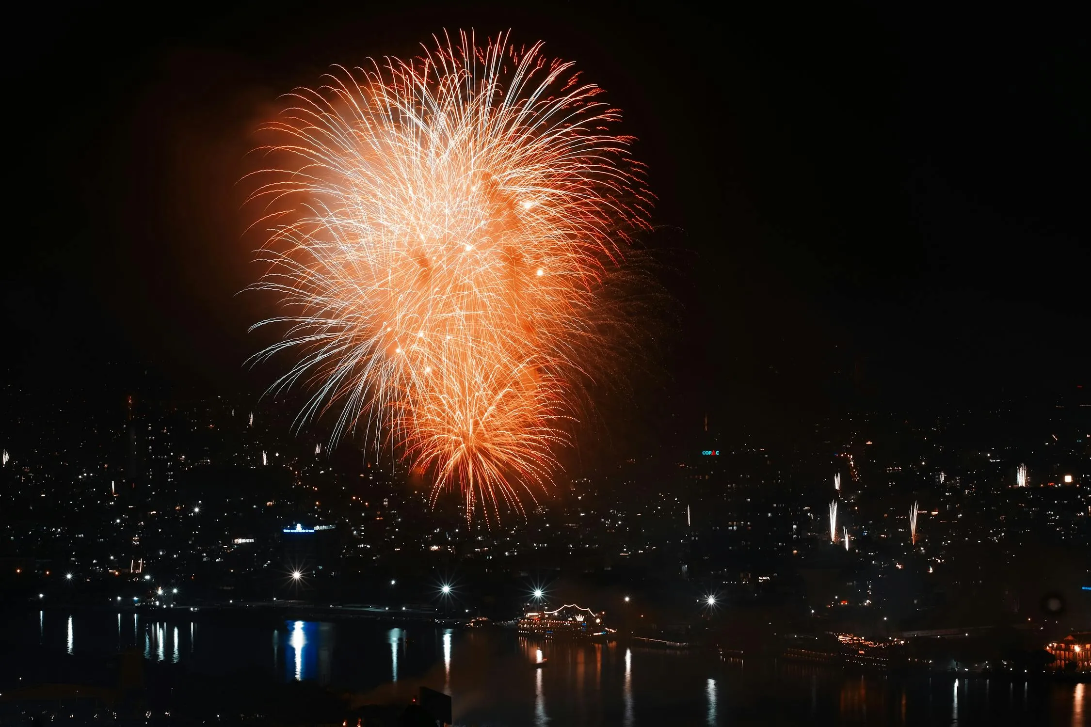 Vibrant fireworks over a quiet city by the water image