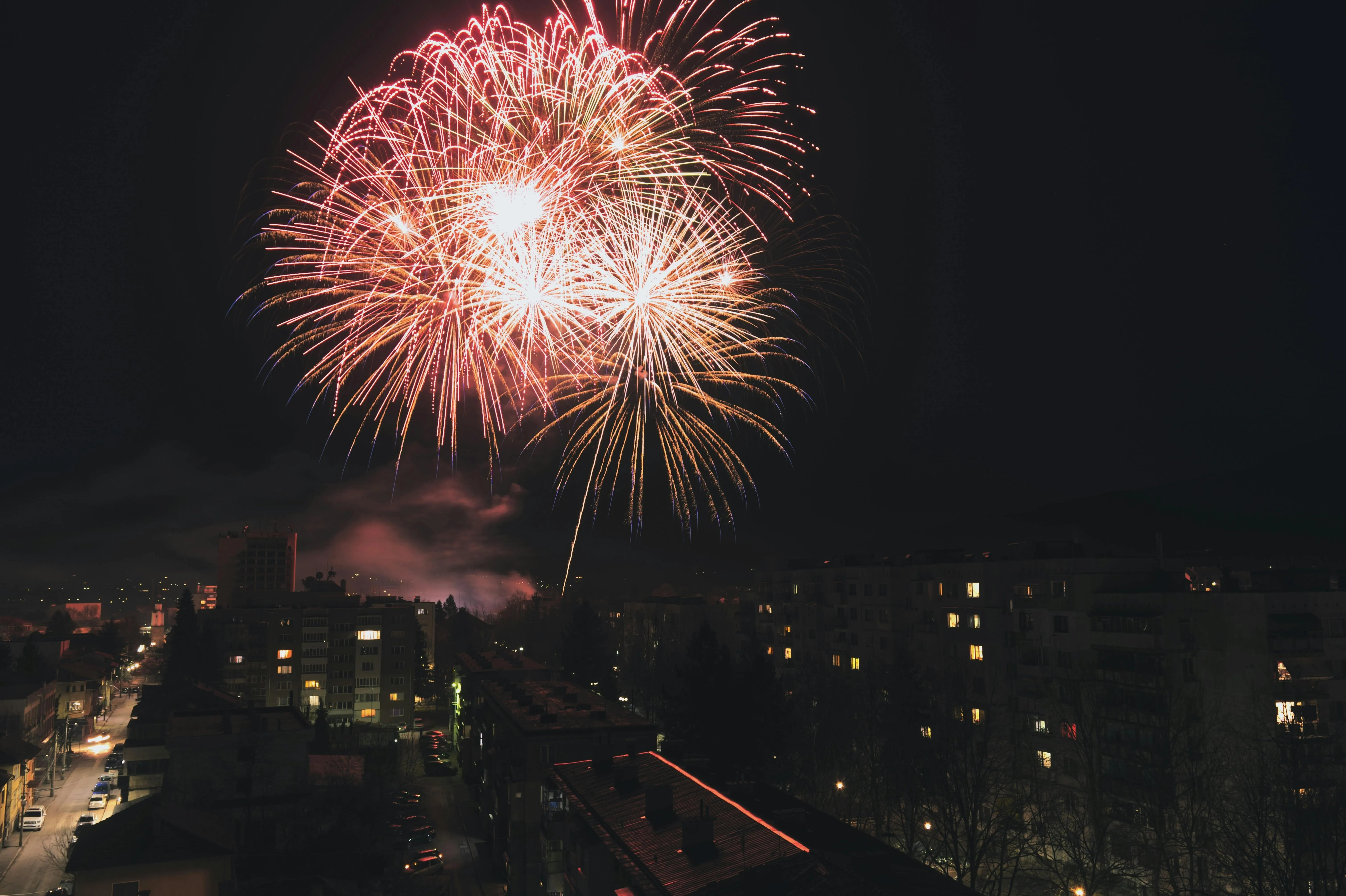 Vibrant fireworks over city buildings lighting up the sky