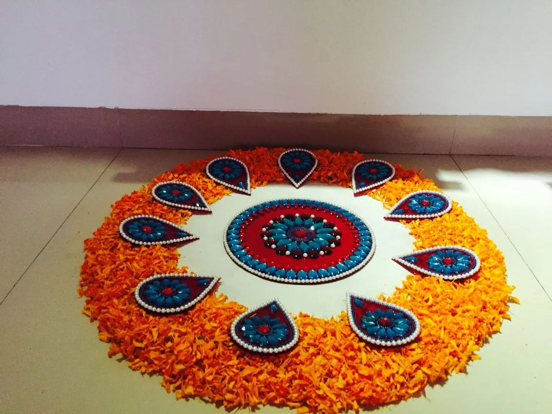 Vibrant orange petal pookolam with blue and red decorations