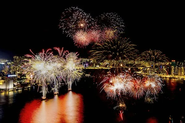 Waterfront Fireworks Reflected over Calm Water at Night
