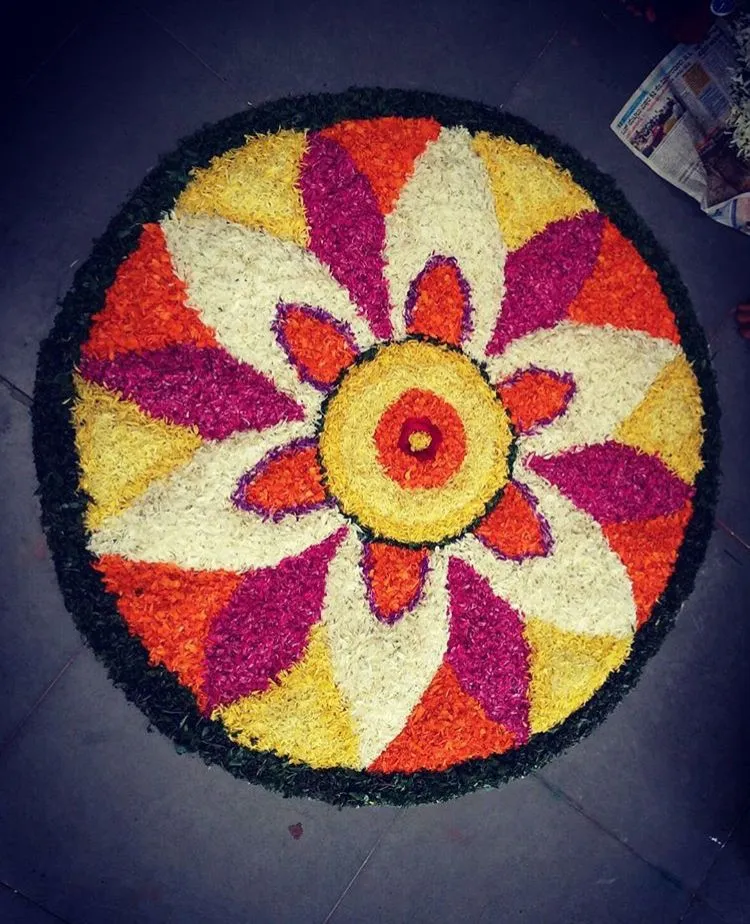 White and purple flower petals with green border pookolam