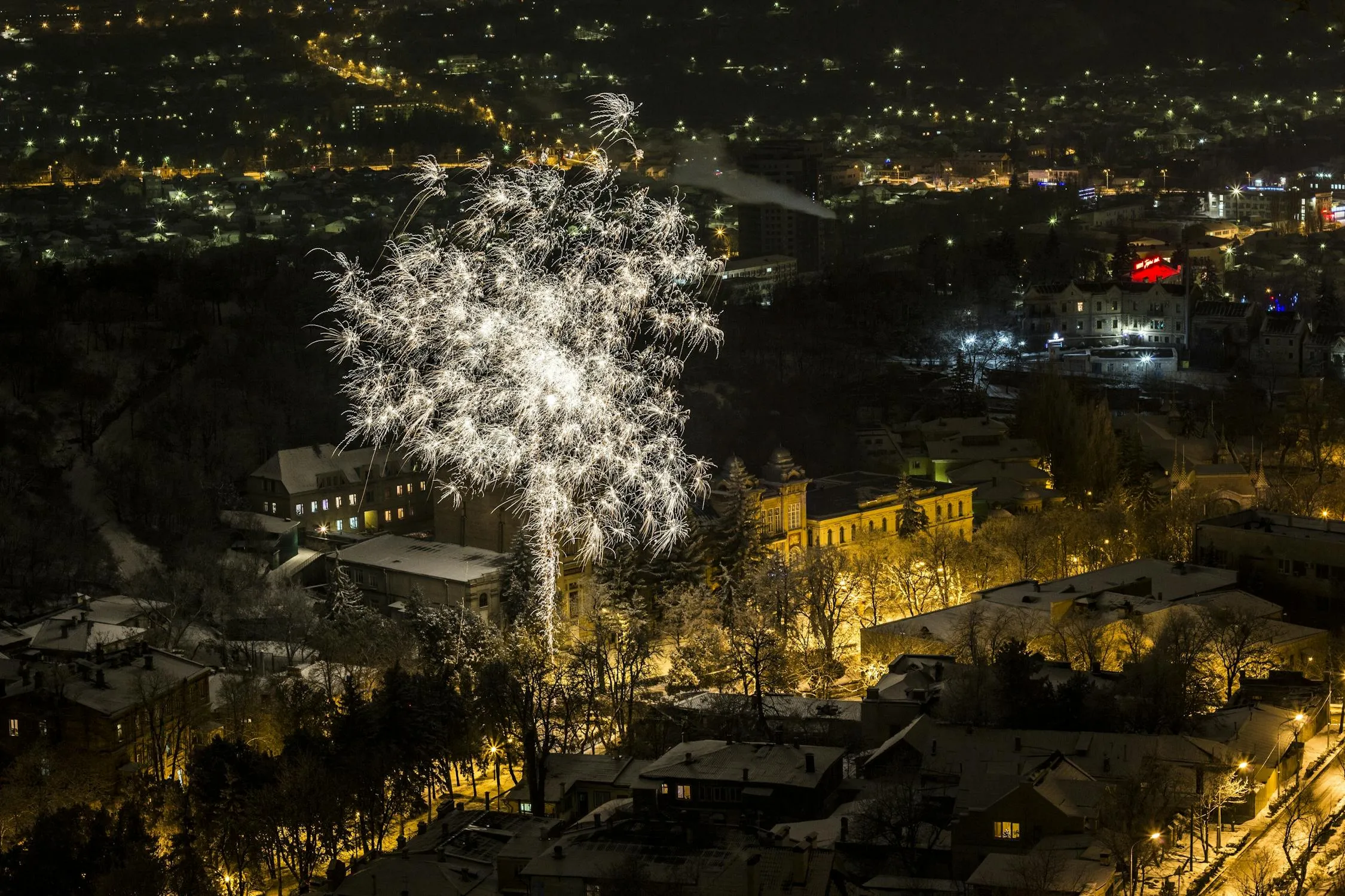 White Fireworks Exploding over a Cityscape at Night