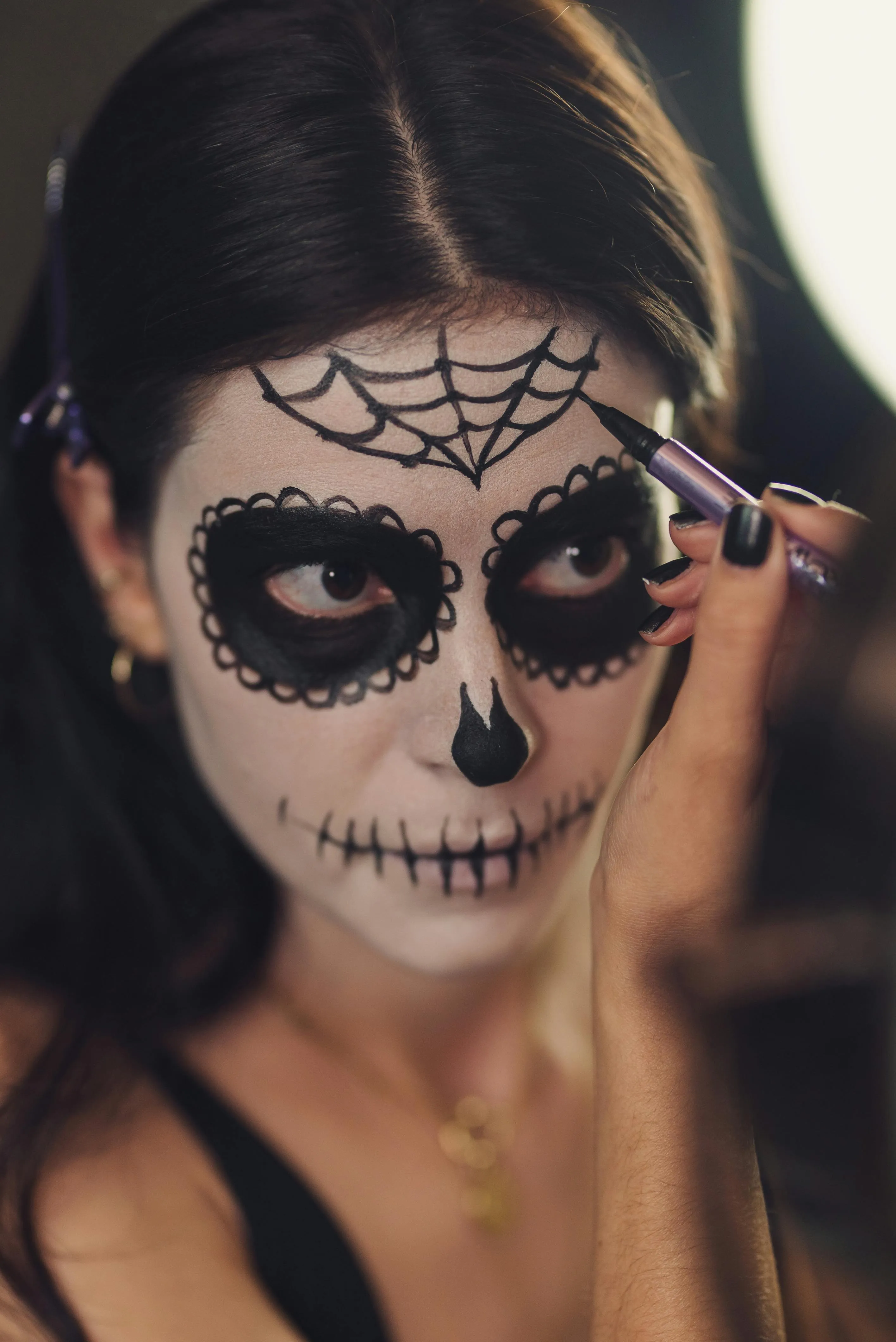 Woman Applying Spider Web Makeup for Halloween Wallpaper