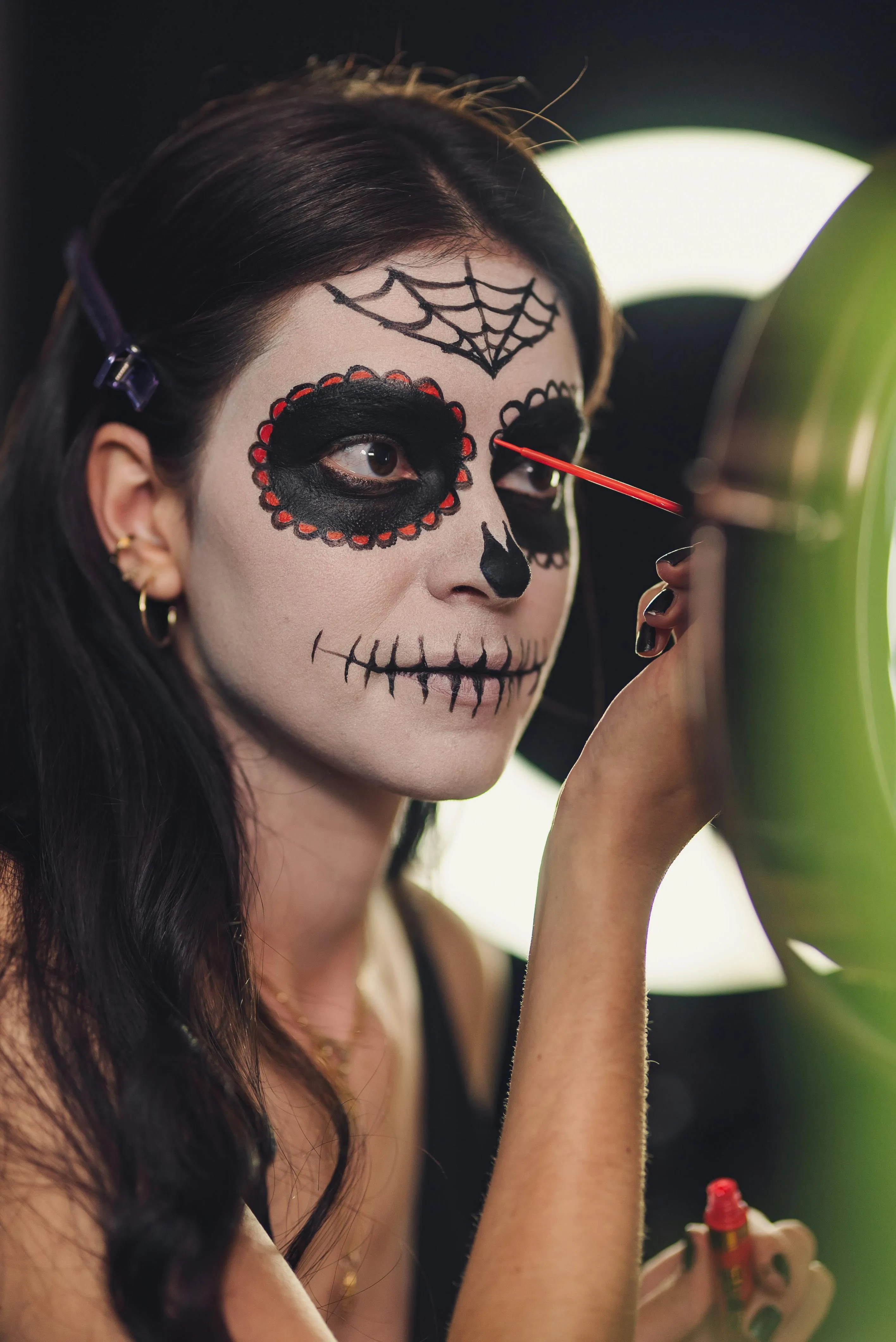 Woman Applying Sugar Skull Makeup in Front of Mirror