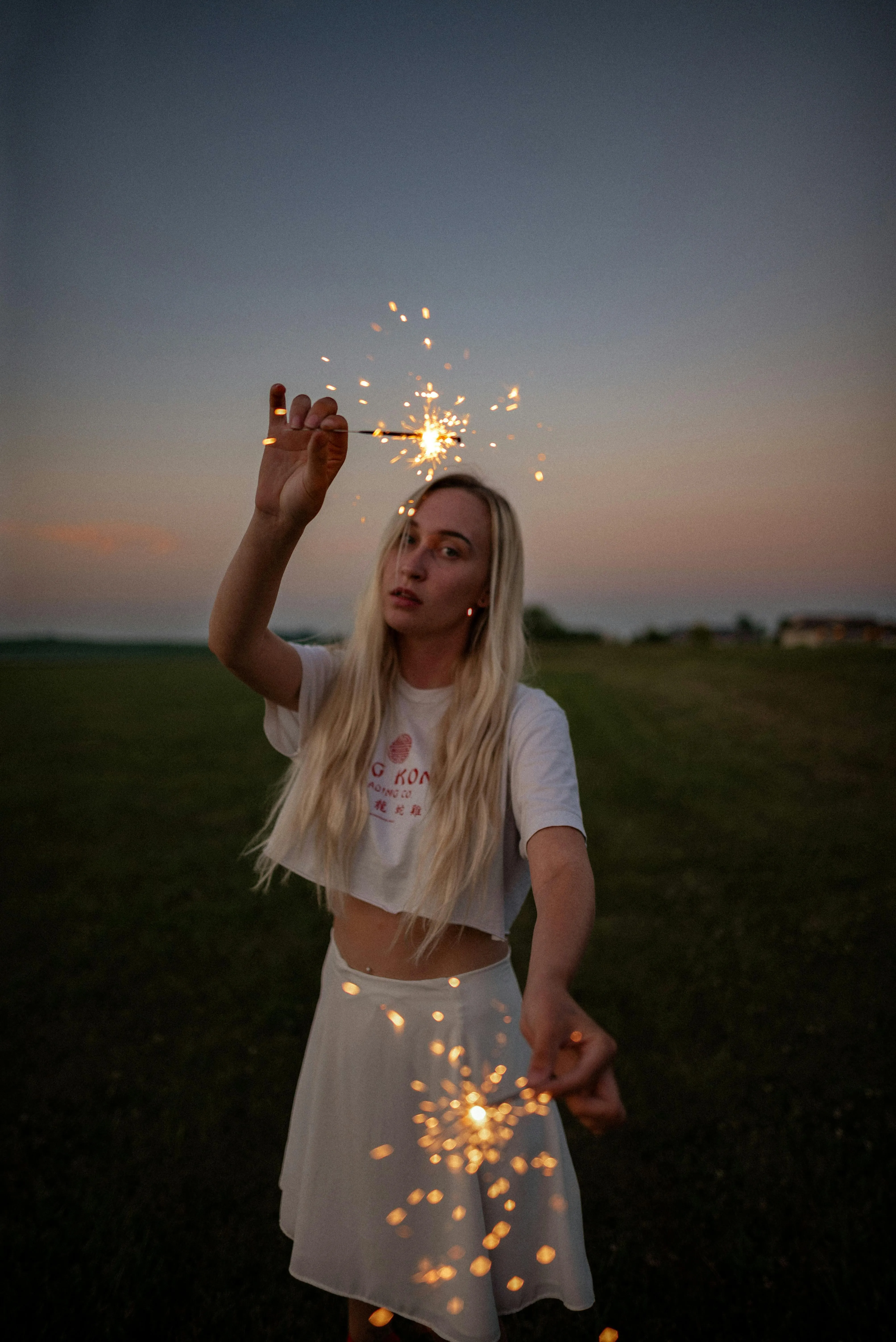 Woman enjoying sparkler under the open sky during sunset