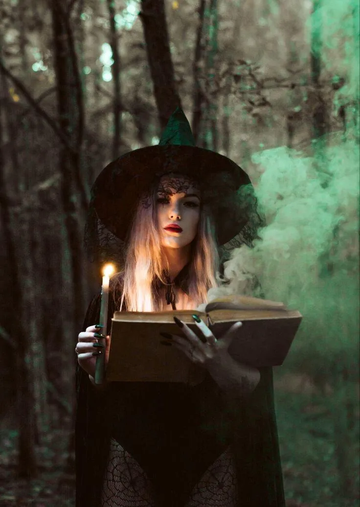 Woman Holding Candle and Book in Forest Wearing Witch Hat