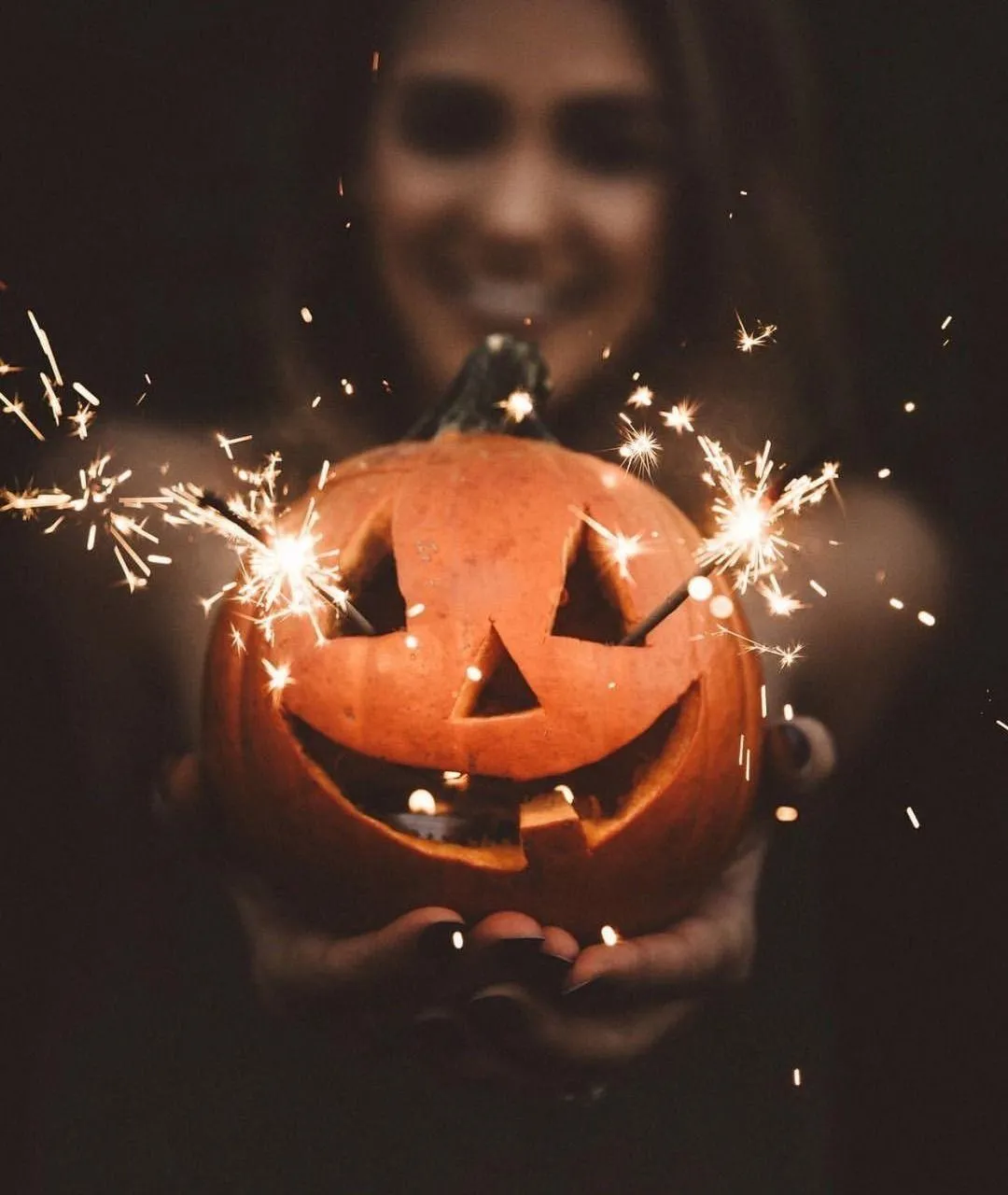 Woman Holding Sparkler Near Jack o Lantern Pumpkin image