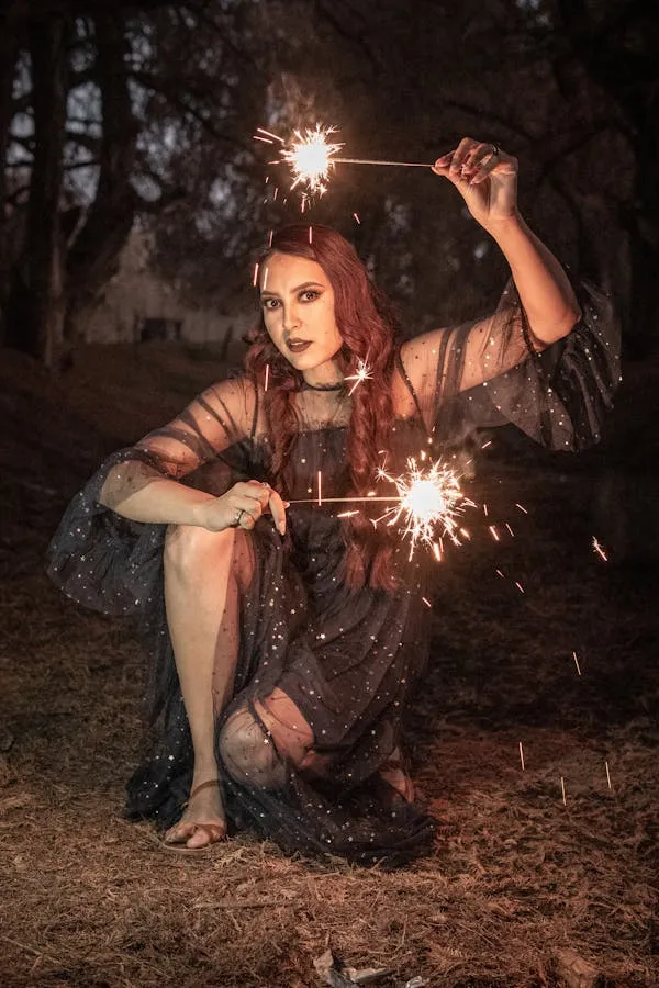 Woman Holding Sparklers with a Beautiful Fireworks Display