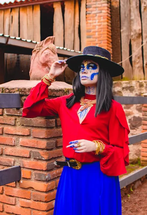 Woman in red shirt and skeleton face paint by brick wall