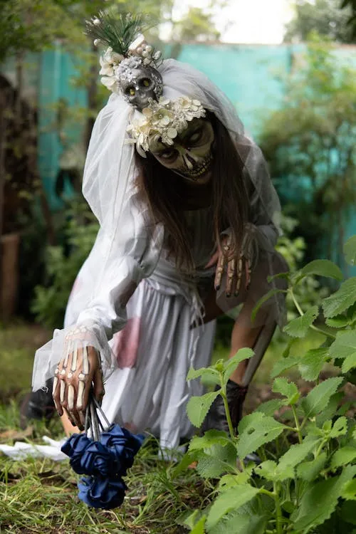 Woman in skeleton costume picking flowers in a garden image