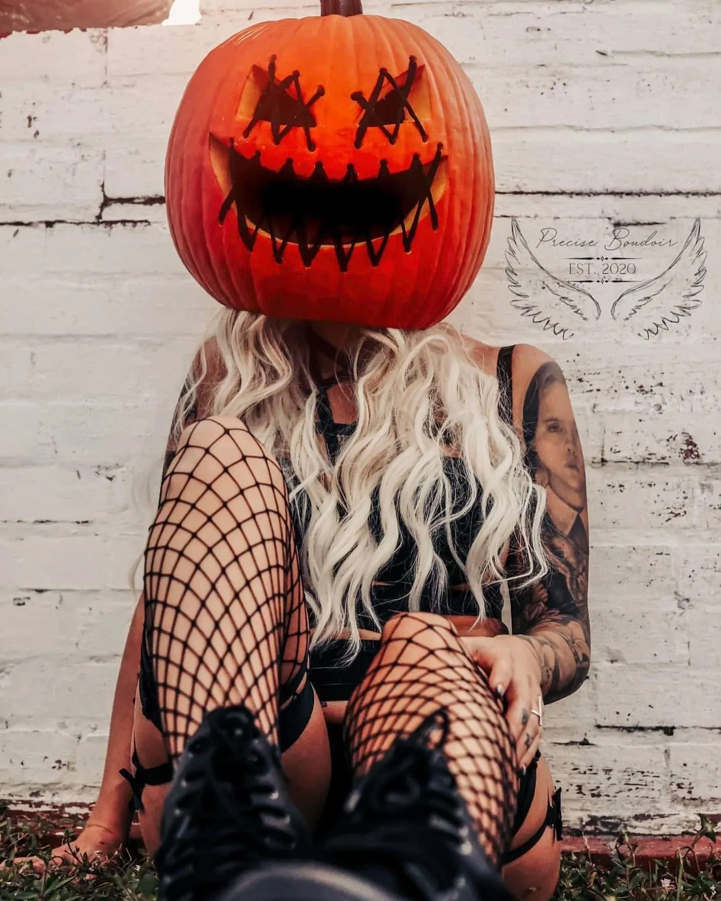 Woman Sitting Against Wall Wearing Pumpkin Mask Wallpaper