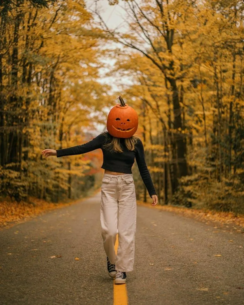 Woman Walking with Pumpkin Head in Autumn Forest Pathway