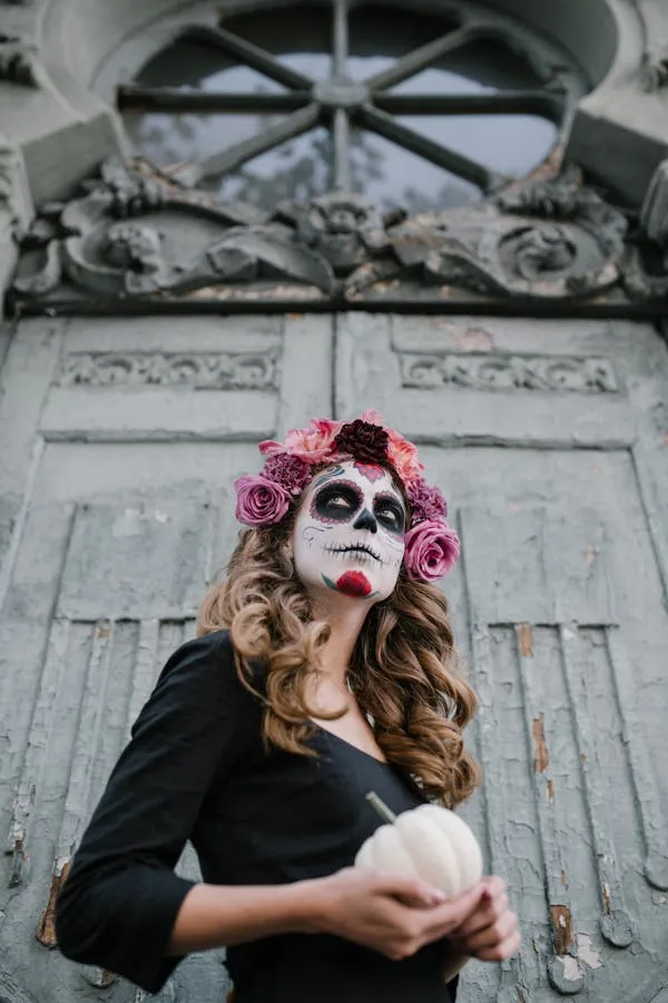 Woman with sugar skull makeup holding a pumpkin image